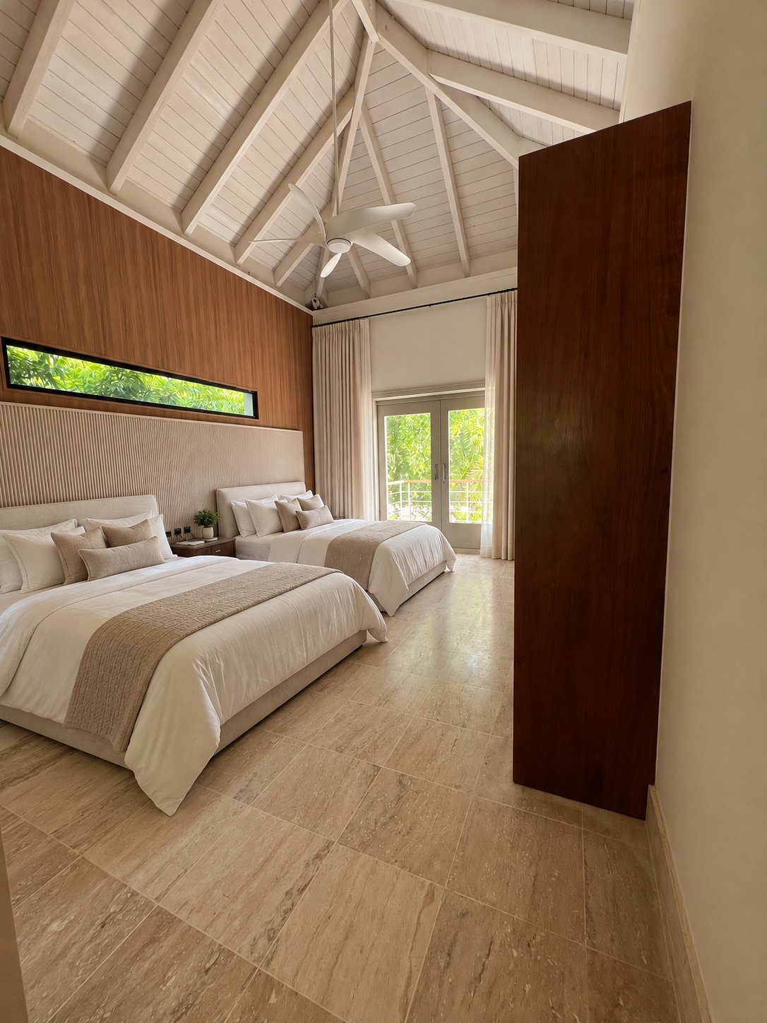 Bedroom with two queen beds and a Murphy bed under a vaulted white ceiling at Villa Espada, Cap Cana