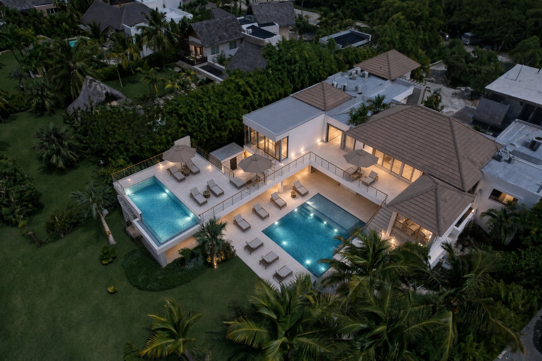 Villa Espada estate lit at dusk with rooftop terrace pool and ground-level pool, Cap Cana