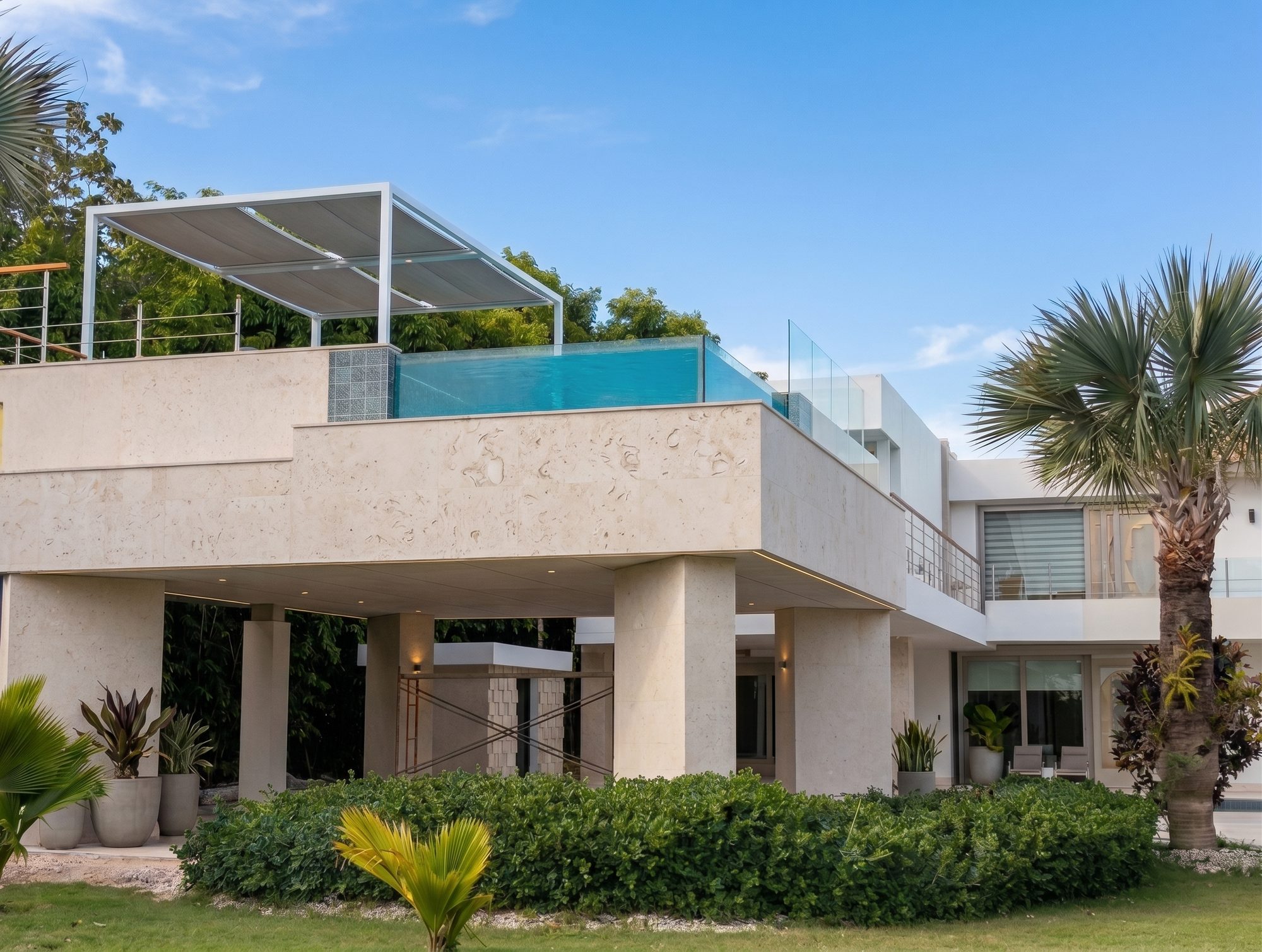 Villa Espada exterior with cantilevered rooftop glass-walled pool and coral stone facade, Cap Cana